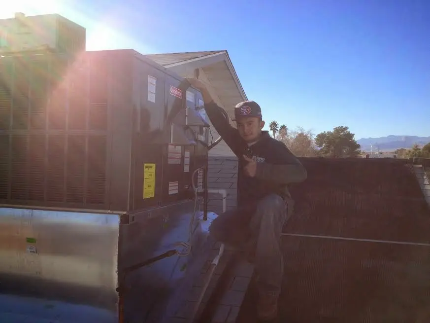 HVAC technician performing AC Tune-Up on a rooftop unit in Chicopee